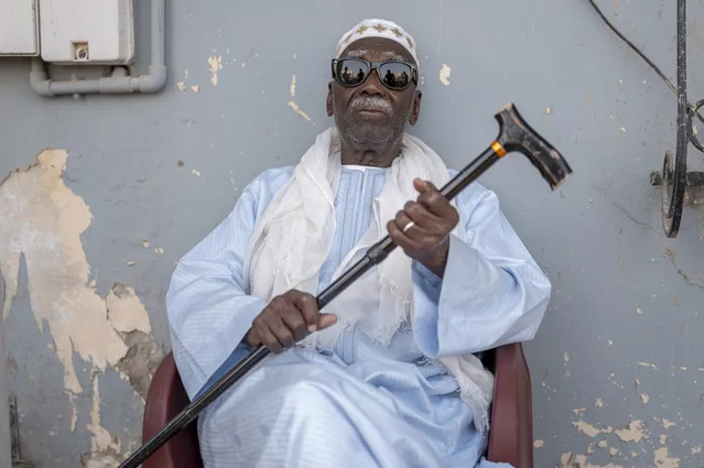 Biram Senghor, dont le père Mbap a été tué en 1944, pose à l'entrée de la maison de son frère Amhet, à Rufisque, au Sénégal, le 28 novembre 2024.