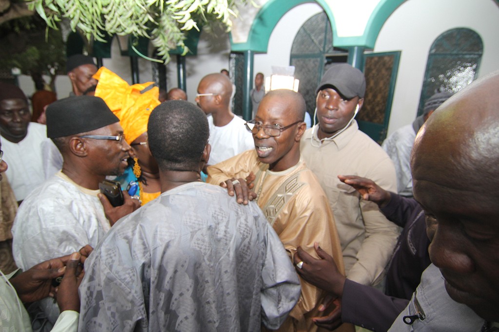 Mamadou Oumar Bocoum  en tenue traditionnelle marron et montures tenant l'épaule d'un ami qui le félicitait